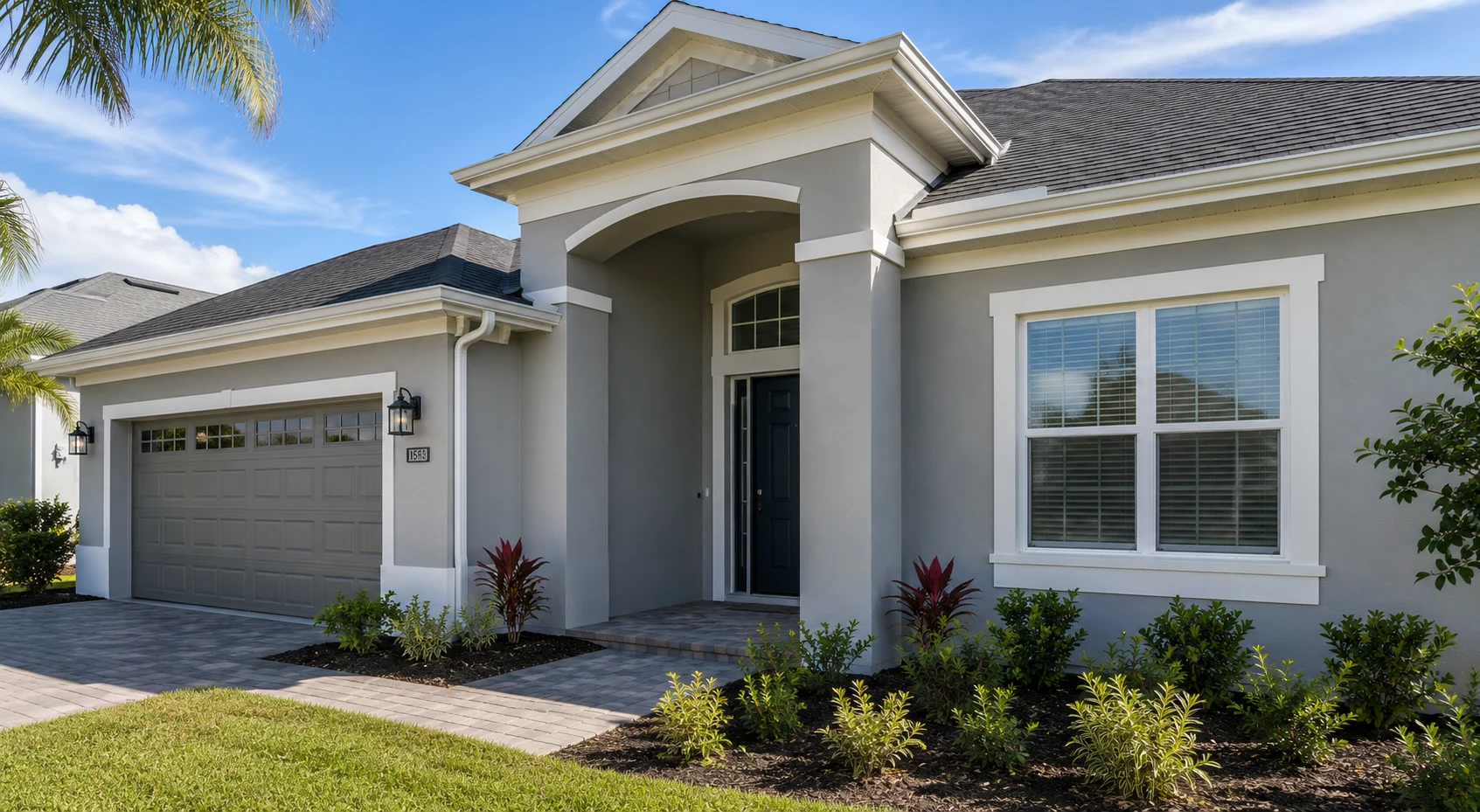 Single-storey Florida stucco home with a light grey body, white trim, taupe garage door and a dark teal front door