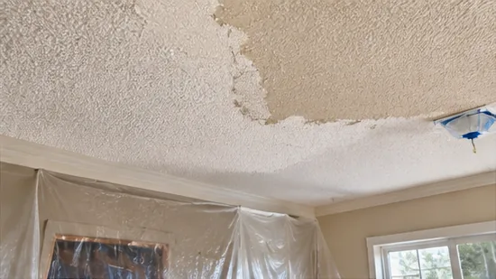 Popcorn ceiling texture partly scraped off, with plastic sheeting protecting the walls and window below